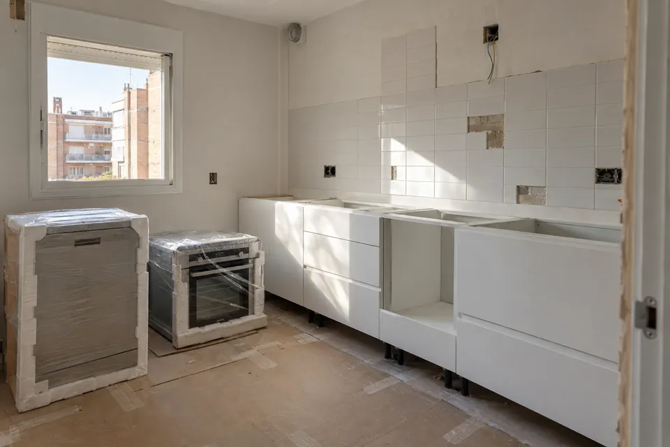 Cocina a medio reformar, con los muebles bajos montados y los electrodomésticos aún embalados