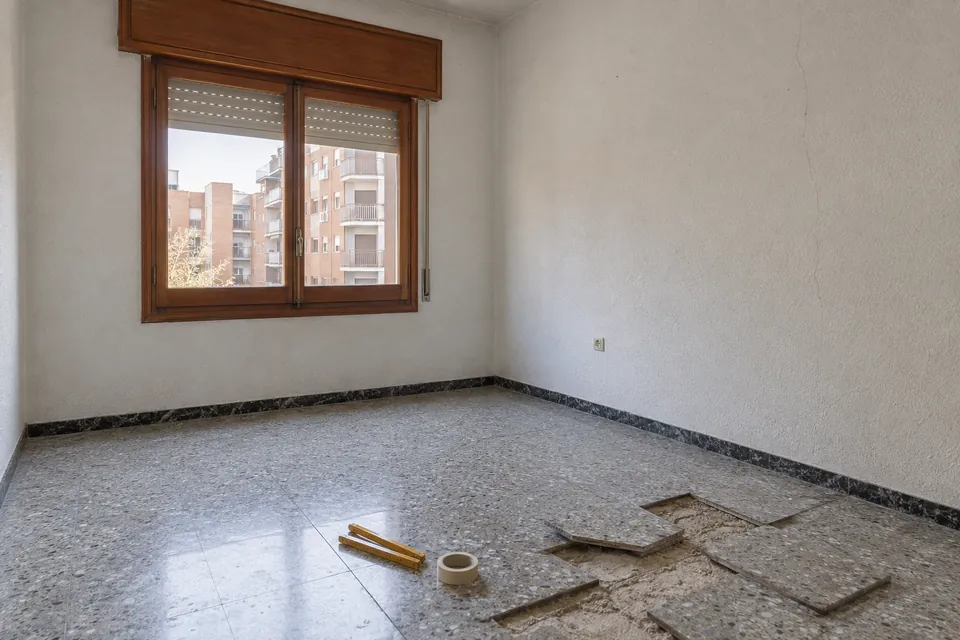 Habitación de un piso antiguo antes de la reforma, con terrazo levantado y paredes de gotelé