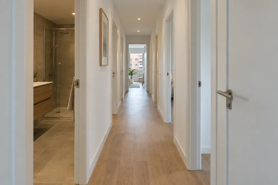 Pasillo de un piso grande reformado, con suelo de madera clara y puertas lacadas en blanco