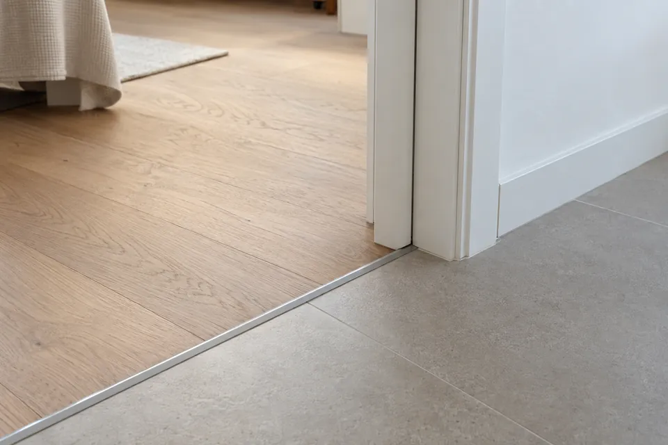 Encuentro entre parquet de roble y porcelánico gris en el paso de una puerta