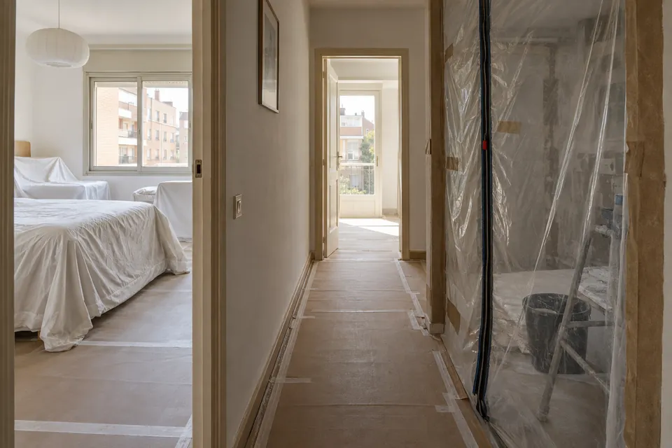 Pasillo de un piso habitado con una puerta sellada con plástico para aislar la zona en obras